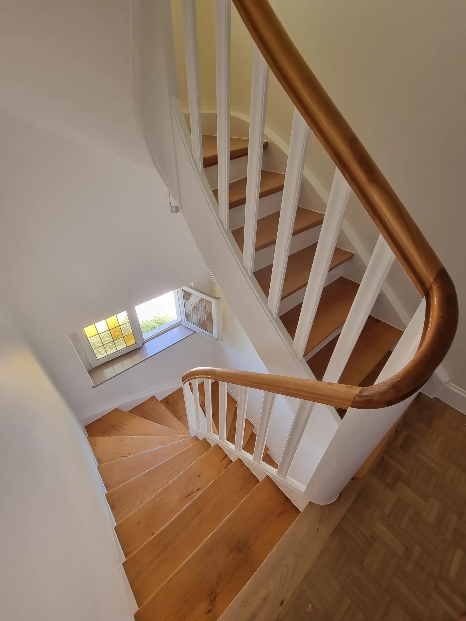 Escalier tournant vu d'en haut, balustres blanches et main courante en bois