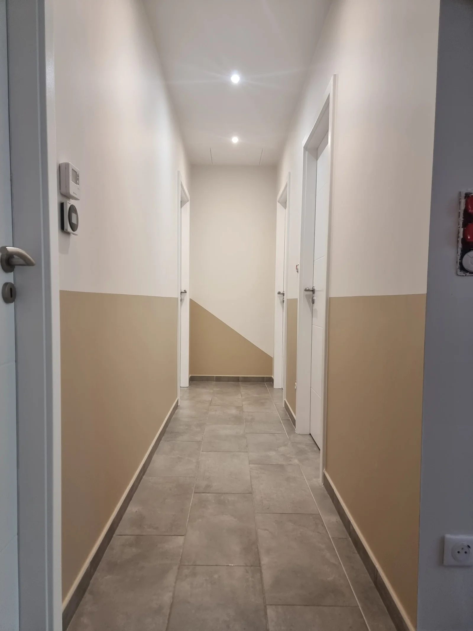Couloir repeint en deux tons, blanc et beige, avec une coupe en diagonale