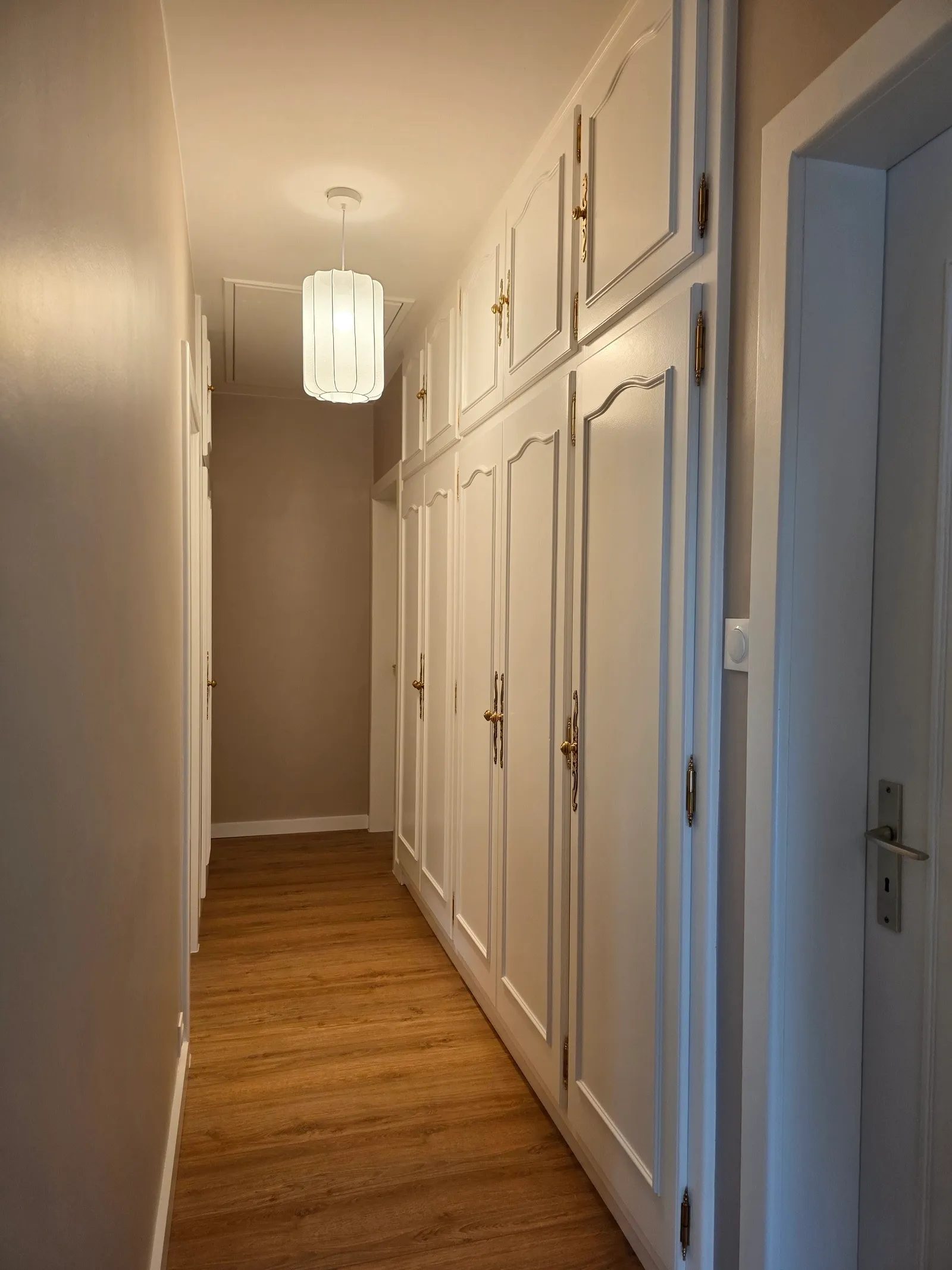 Couloir avec placards en bois laqués blanc et poignées dorées